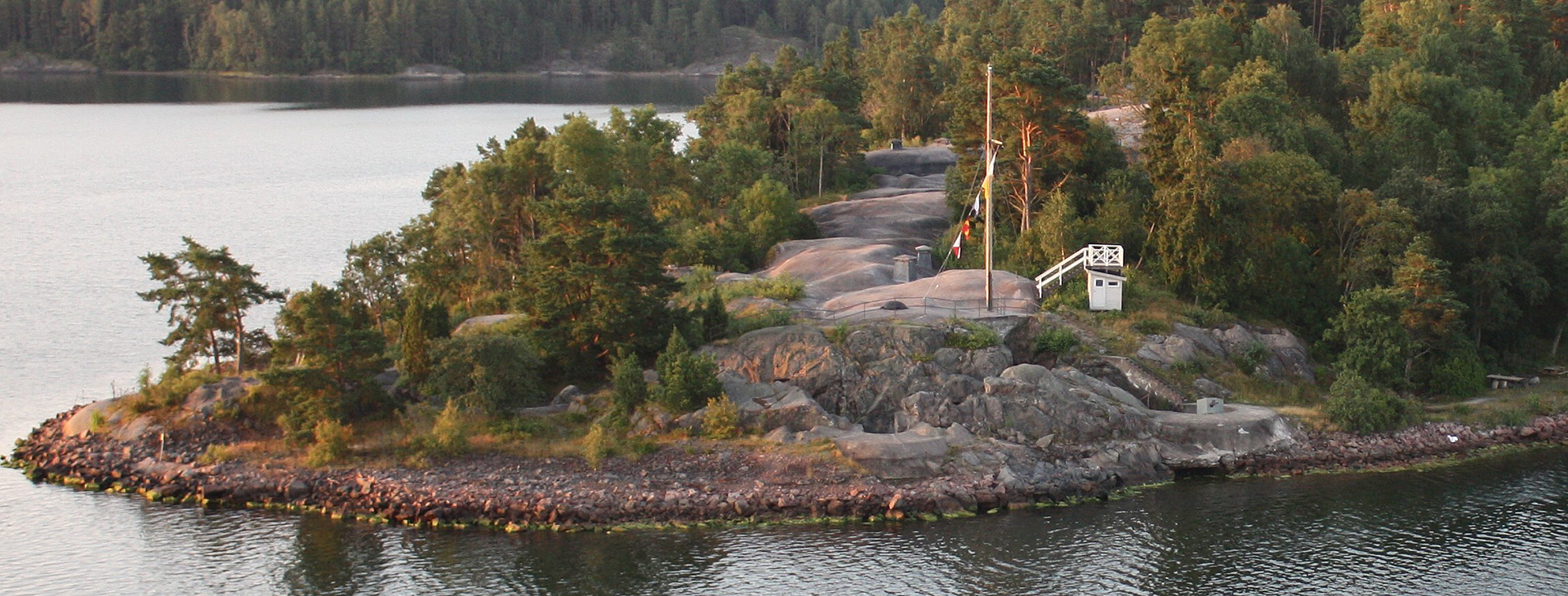 En ö med mycket träd omgärdas av vatten.