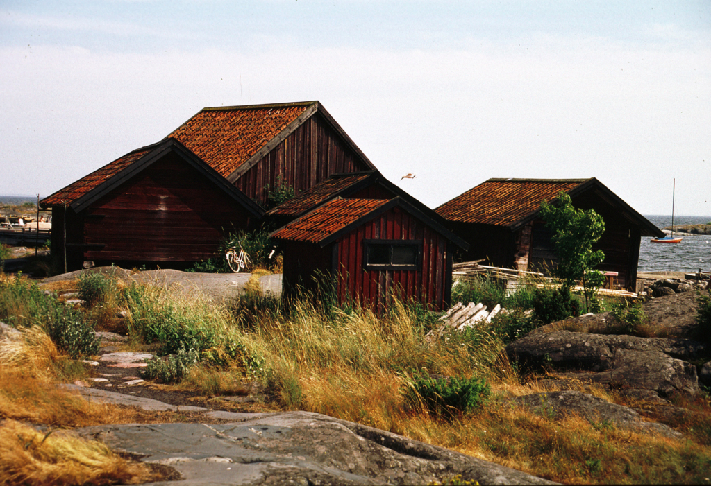 Små hus som står på klipporna. Havet syns i bakgrunden. Det är sommar.