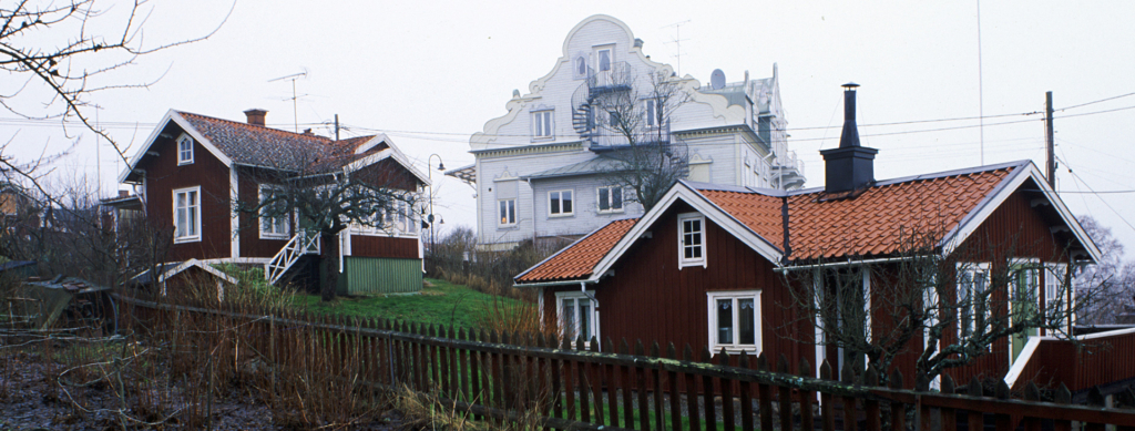 Ett stort hus med två trähus som står nedanför.