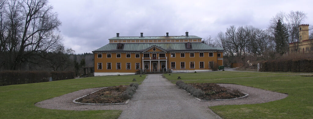 Ett stort hus med många fönster, det har en stor gräsplan framför sig.