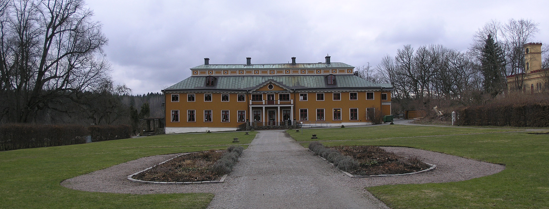 Ett stort hus med många fönster, det har en stor gräsplan framför sig.