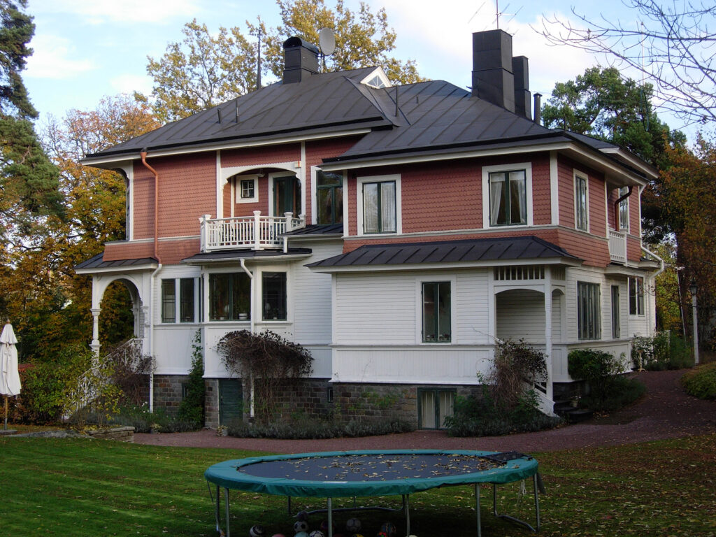 En stort hus med en studsmatta på gräsmattan framför huset.