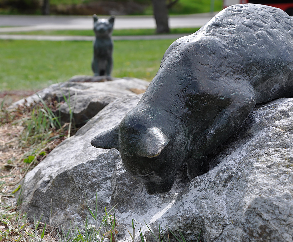 En skulptur av en katt som sitter på en sten.