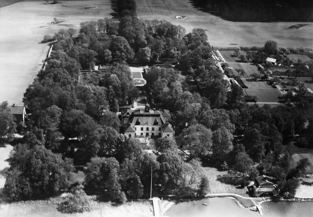 Flygbild över ett slott vid vatten och grönska