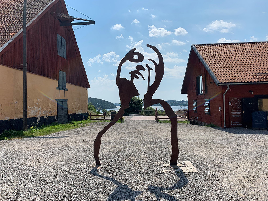 Skulptur av ett ansikte med överkropp där bakgrunden blir en del av verket.