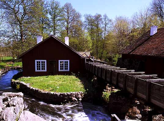 En hus som står nära ett vattendrag. Framför huset är det gräs.