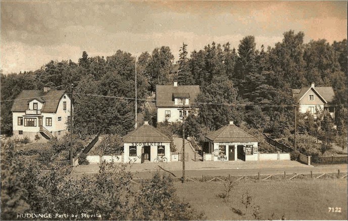 En svartvit bild där de två paviljongerna syns mitt i bild. Bakom ligger tre villor inbäddade i grönska.