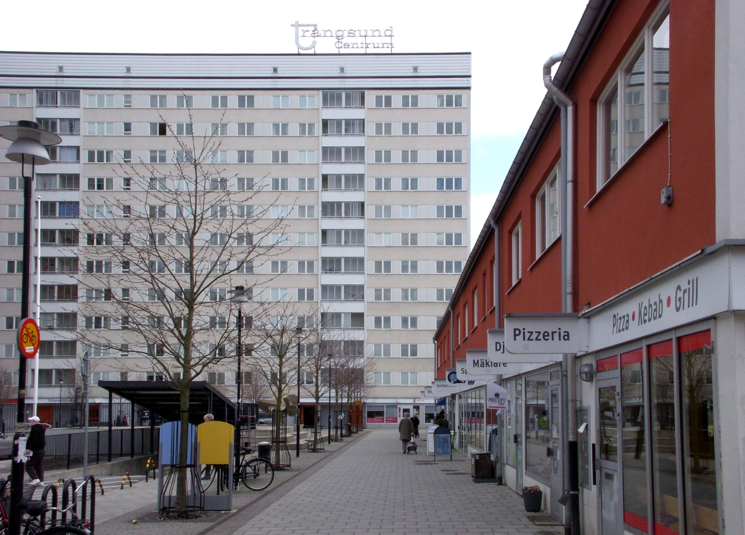 Ett lägre hus med röd fasad till vänster och ett tolv våningar högt skivhus rakt fram.